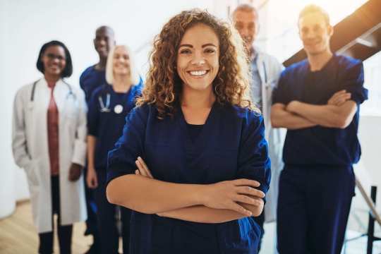 a group of people standing in front of a person in blue scrubs