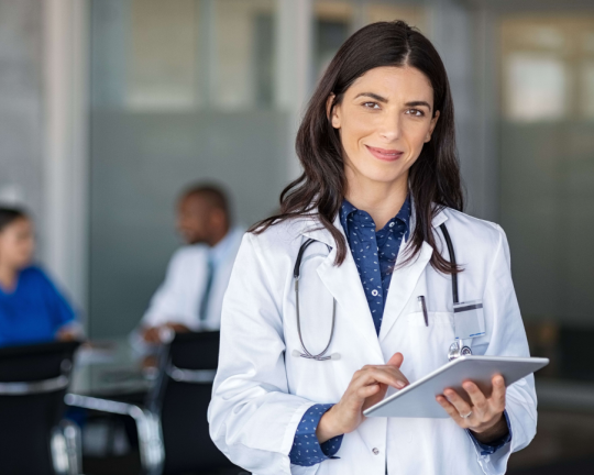 a person in a white coat holding a tablet